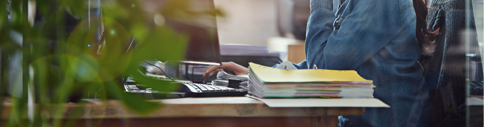 Woman working with paperwork scattered on her desk.